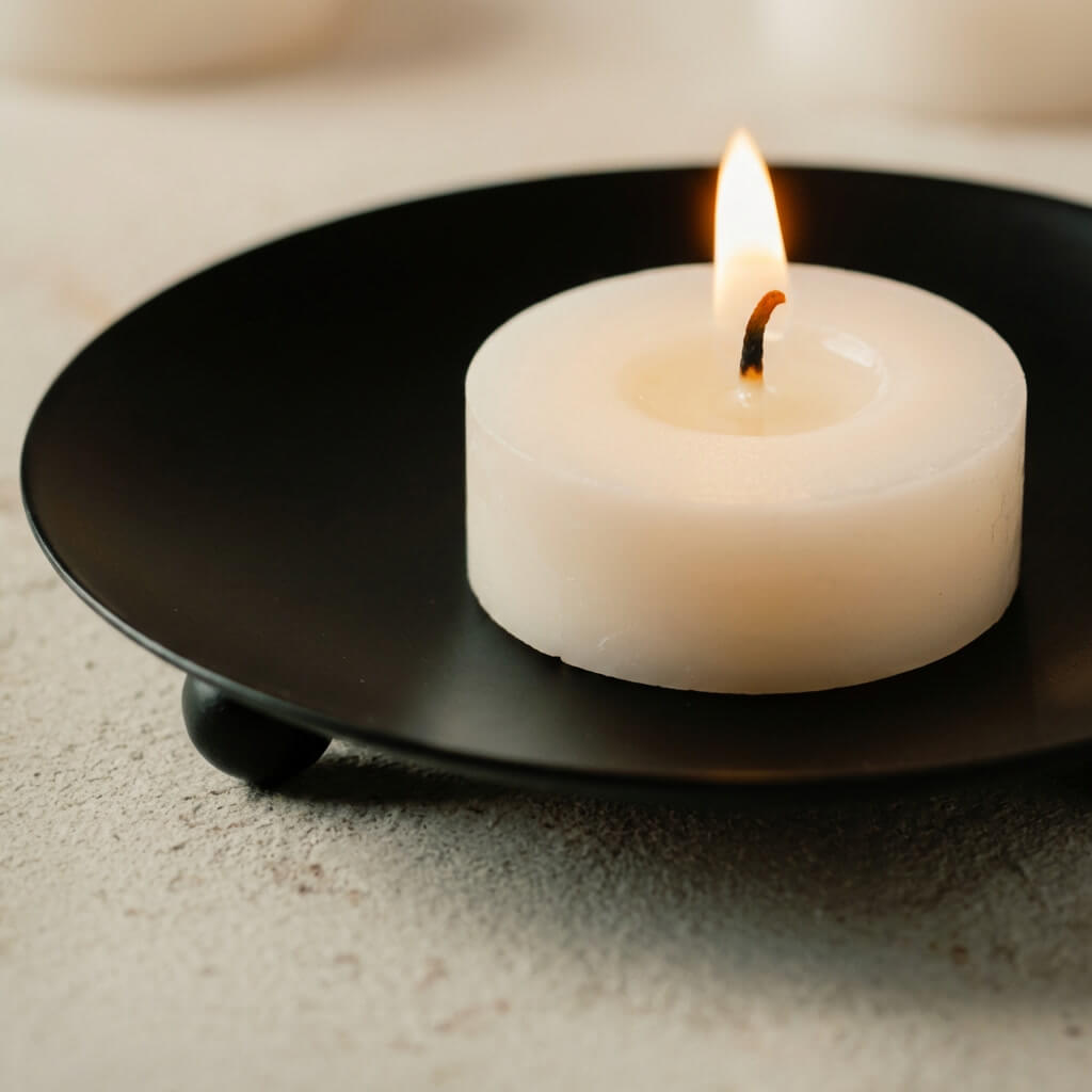 Nahaufnahme brennendes Bio Sojawachs Teelicht auf schwarzem Metallhalter - Duftprobe handgemacht Deutschland